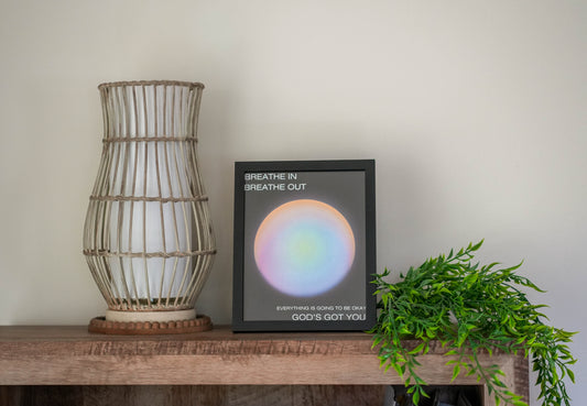 Decorative lamp, framed artwork with motivational quote, and plant on a wooden surface.