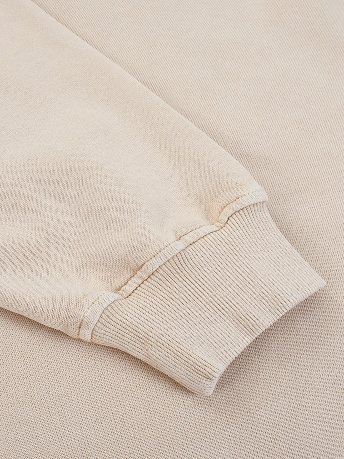 Close-up of a beige sweater sleeve on a matching background