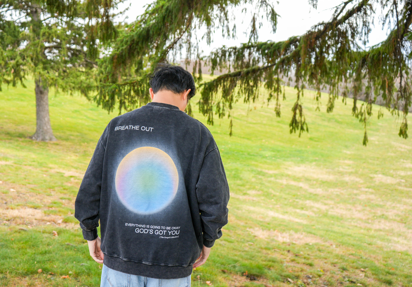 Person wearing a black sweatshirt with a colorful design outdoors
