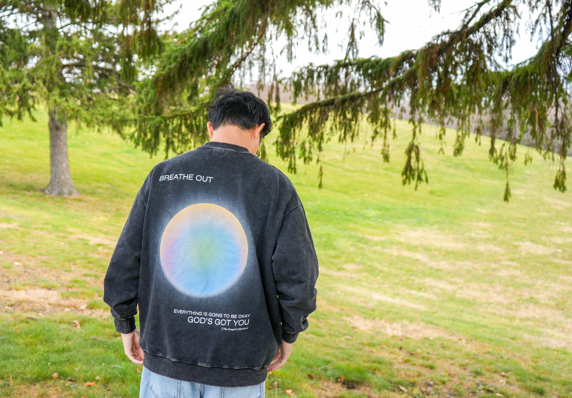 Person wearing a black sweatshirt with a colorful design outdoors